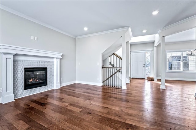 unfurnished living room with a tiled fireplace, crown molding, and dark hardwood / wood-style flooring