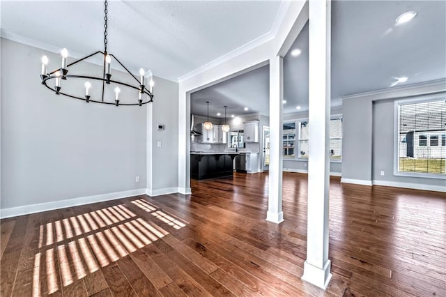 unfurnished dining area with ornamental molding, dark hardwood / wood-style floors, a chandelier, and ornate columns