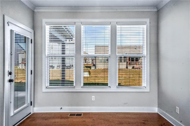 empty room featuring dark wood-type flooring and ornamental molding