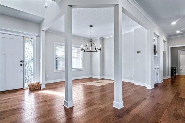 foyer featuring an inviting chandelier, dark wood-type flooring, and ornamental molding