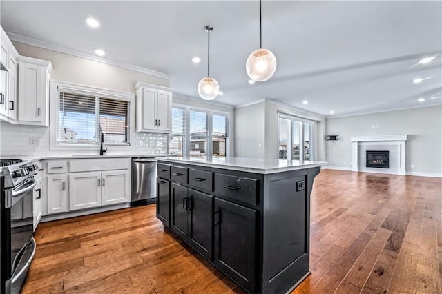 kitchen with sink, hanging light fixtures, stainless steel appliances, a center island, and white cabinets