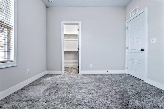 unfurnished bedroom featuring a closet, carpet flooring, and a spacious closet