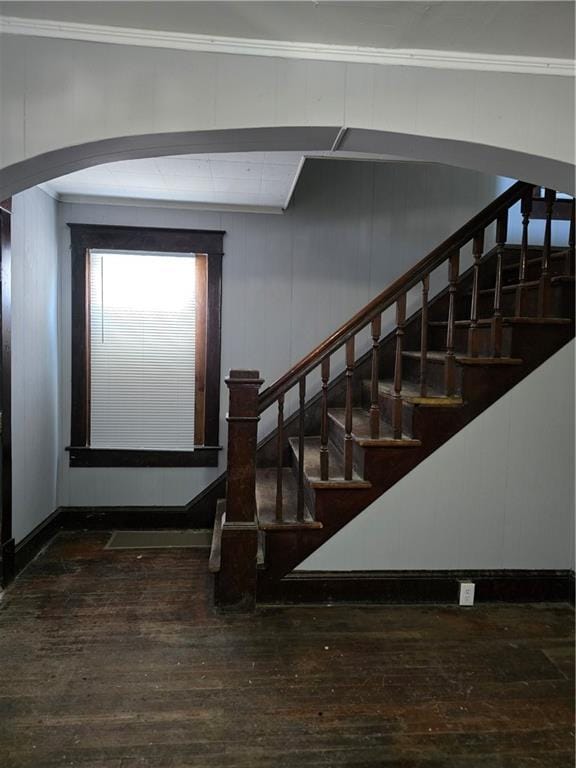 stairs featuring ornamental molding, arched walkways, and hardwood / wood-style floors