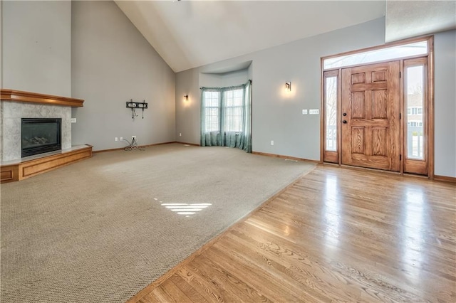 unfurnished living room with light hardwood / wood-style floors, a tile fireplace, and lofted ceiling