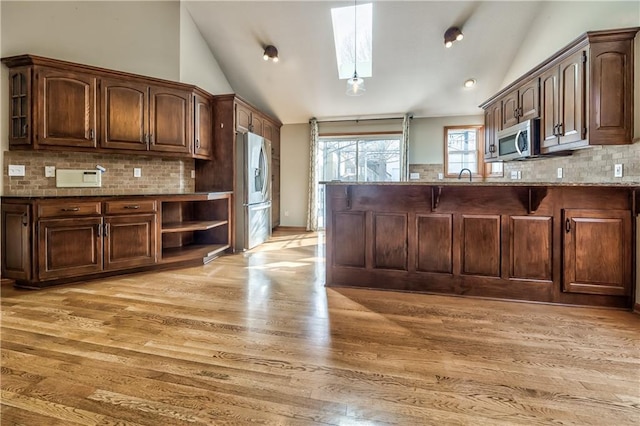 kitchen with dark brown cabinets, lofted ceiling with skylight, and stainless steel appliances