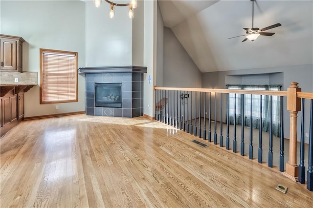 unfurnished living room featuring vaulted ceiling, ceiling fan, light hardwood / wood-style flooring, and a fireplace