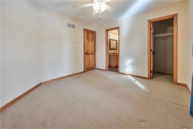 unfurnished bedroom with ceiling fan, light carpet, a closet, and ensuite bath