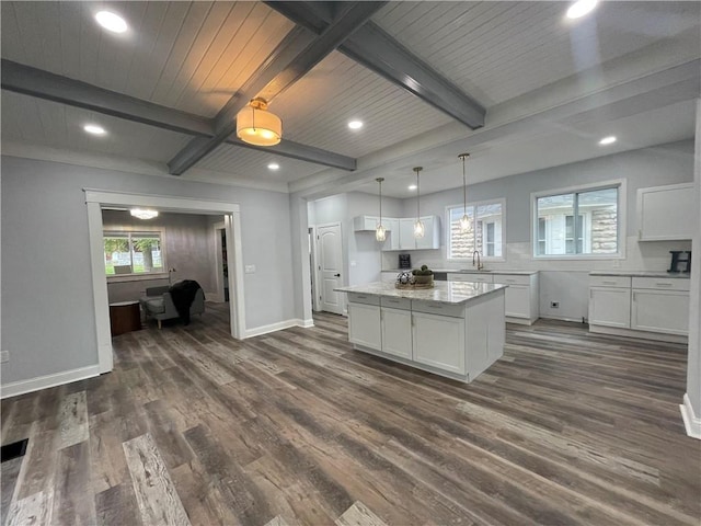 kitchen with beam ceiling, a center island, white cabinetry, and dark wood-type flooring