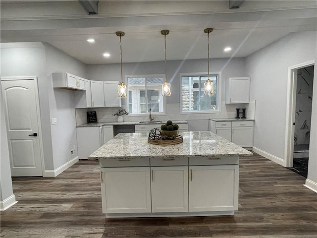 kitchen featuring a center island, white cabinetry, light stone countertops, and tasteful backsplash