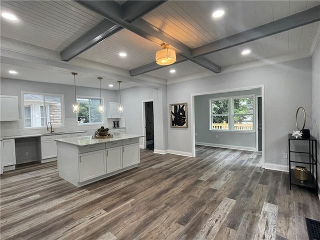 kitchen featuring pendant lighting, a center island, white cabinets, light stone countertops, and dark hardwood / wood-style flooring