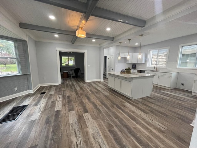 kitchen featuring a center island, dark wood-type flooring, white cabinets, decorative light fixtures, and beam ceiling