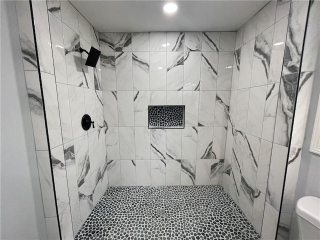 bathroom featuring a tile shower and toilet