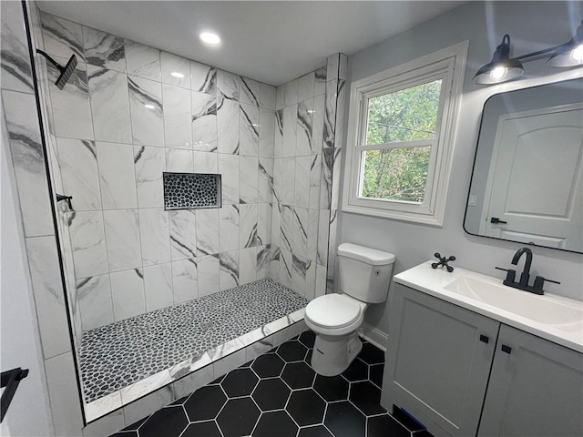 bathroom featuring a tile shower, vanity, toilet, and tile patterned floors