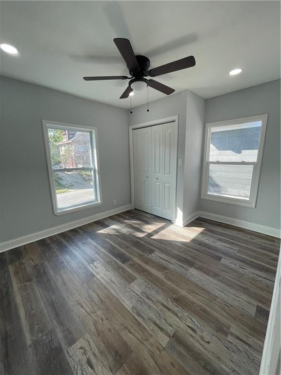 unfurnished bedroom featuring dark hardwood / wood-style flooring, ceiling fan, and a closet