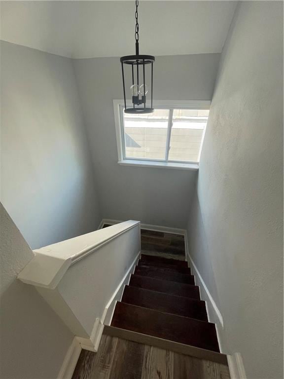 stairs with hardwood / wood-style floors and a chandelier