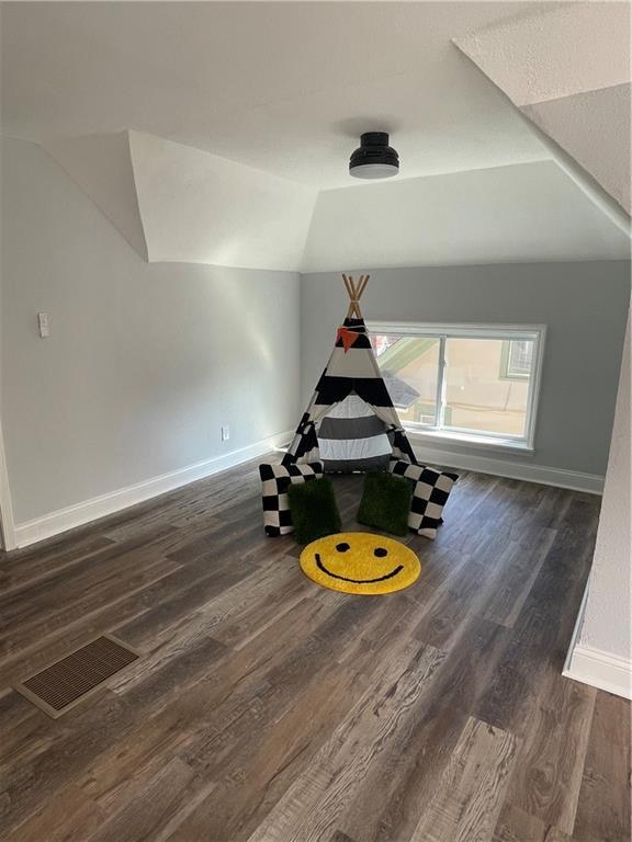 rec room featuring vaulted ceiling and dark wood-type flooring