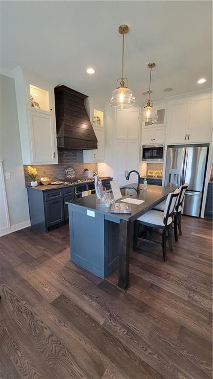 kitchen featuring blue cabinetry, white cabinetry, stainless steel appliances, and premium range hood