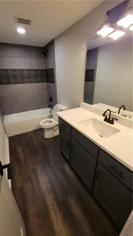 full bathroom with shower / tub combination, vanity, hardwood / wood-style flooring, and toilet