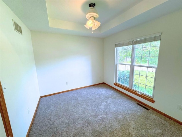 carpeted empty room featuring a tray ceiling and ceiling fan