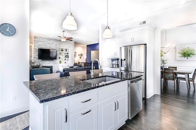 kitchen featuring dark wood-type flooring, sink, white cabinetry, a center island with sink, and stainless steel appliances