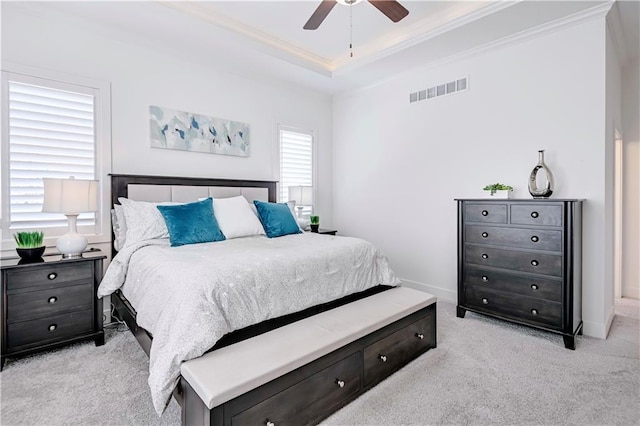 bedroom with crown molding, light colored carpet, a raised ceiling, and ceiling fan