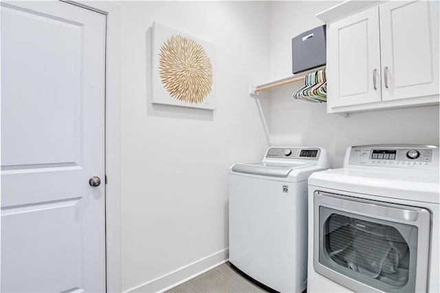 washroom with cabinets, light hardwood / wood-style floors, and washer and dryer