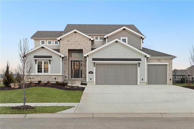 view of front of home with an attached garage, a shingled roof, stone siding, driveway, and a front lawn