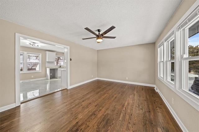 unfurnished room with a textured ceiling, dark hardwood / wood-style flooring, plenty of natural light, and ceiling fan