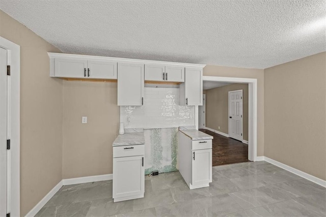 kitchen with white cabinets, a textured ceiling, and tasteful backsplash