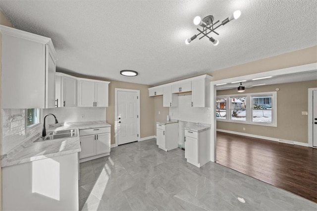 kitchen featuring a textured ceiling, plenty of natural light, white cabinetry, and sink