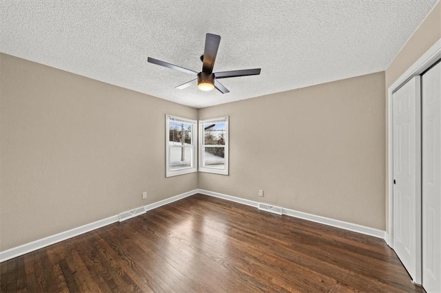 unfurnished bedroom featuring ceiling fan, dark hardwood / wood-style floors, a textured ceiling, and a closet