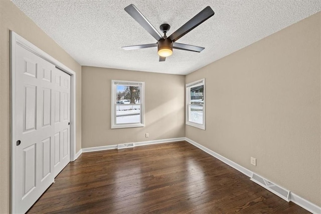 unfurnished bedroom featuring a textured ceiling, ceiling fan, a closet, and dark hardwood / wood-style floors