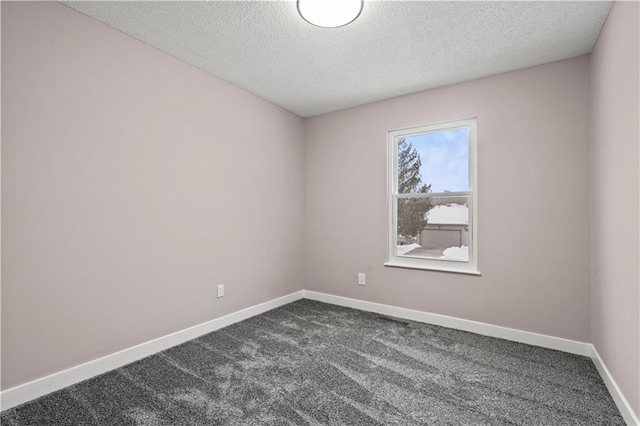 spare room featuring a textured ceiling and dark carpet