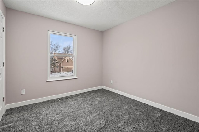 empty room with dark carpet and a textured ceiling