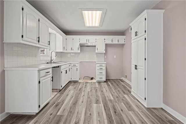 kitchen with stainless steel dishwasher, light hardwood / wood-style floors, tasteful backsplash, white cabinets, and sink