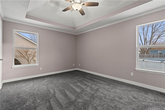 carpeted empty room with ornamental molding, a raised ceiling, and ceiling fan