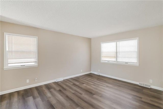 unfurnished room with a textured ceiling and dark wood-type flooring