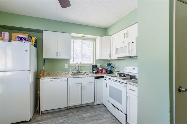 kitchen with white appliances, a textured ceiling, light hardwood / wood-style flooring, white cabinets, and sink