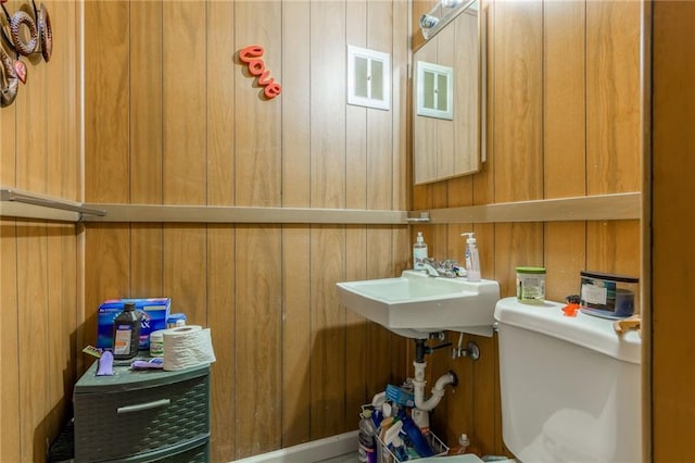 bathroom with sink, wood walls, and toilet