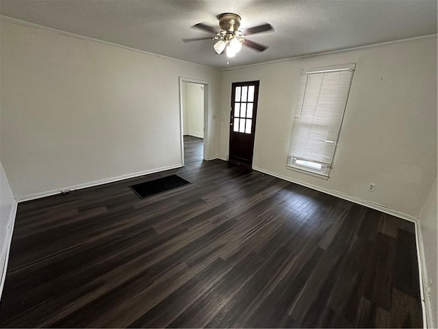 empty room with ceiling fan, crown molding, and dark wood-type flooring