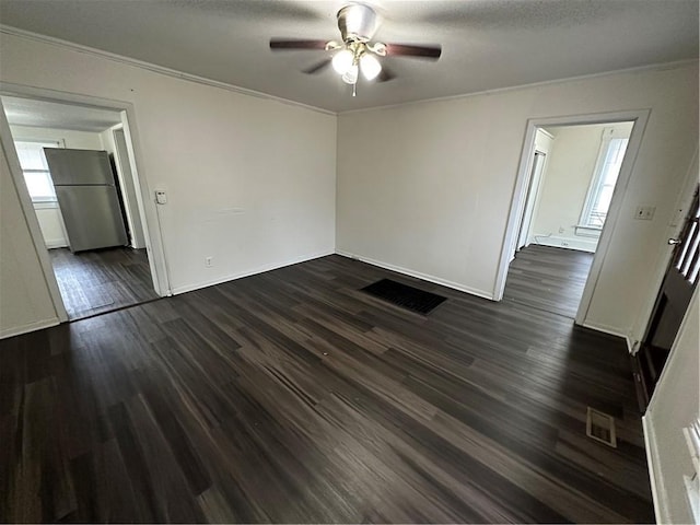 spare room with a textured ceiling, dark hardwood / wood-style floors, ceiling fan, and crown molding