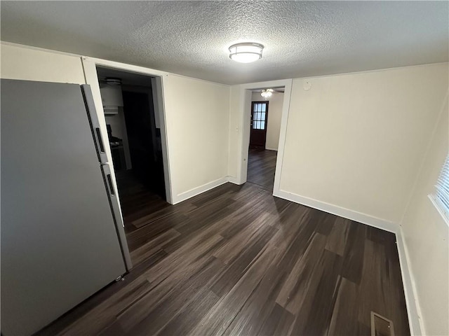 spare room featuring a textured ceiling, ceiling fan, and dark wood-type flooring