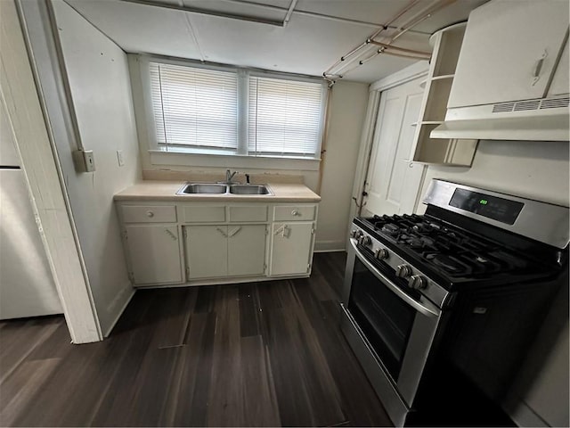 kitchen with dark wood-type flooring, white cabinets, sink, range hood, and stainless steel range with gas stovetop