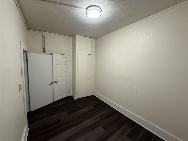 unfurnished bedroom with dark hardwood / wood-style floors, a textured ceiling, and a closet