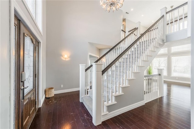 foyer entrance with a towering ceiling, a chandelier, and dark hardwood / wood-style floors