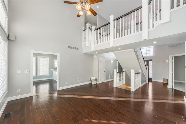 unfurnished living room featuring a high ceiling, ceiling fan, and dark hardwood / wood-style floors