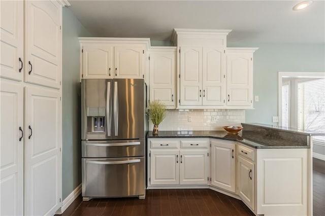 kitchen featuring white cabinetry, tasteful backsplash, dark stone counters, stainless steel refrigerator with ice dispenser, and dark hardwood / wood-style flooring