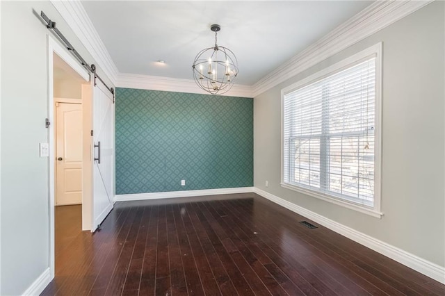 empty room with a notable chandelier, crown molding, a barn door, and dark hardwood / wood-style floors