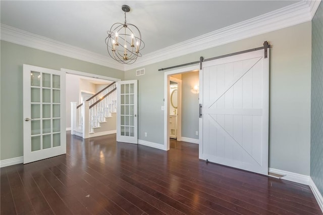 spare room with french doors, a notable chandelier, a barn door, and dark wood-type flooring