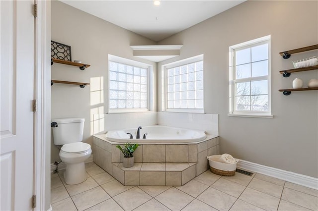 bathroom with toilet, tile patterned flooring, and a relaxing tiled tub